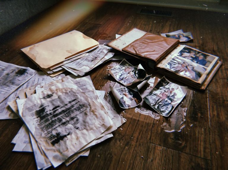 Soaked important papers and family photos ruined by water on a wet floor